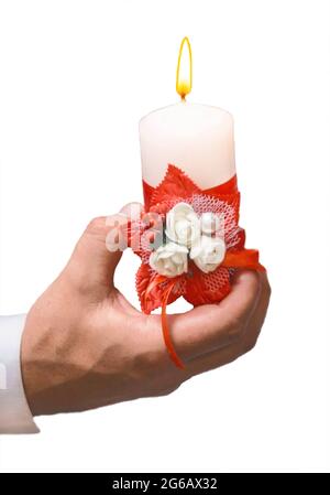 The man's hand holds a decorative light burning candle on a white background, an isolated, soft focus. Stock Photo