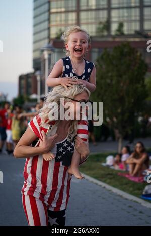 New York, USA. 4th Jul, 2021. A young girl laughs while on her mother’s shoulders prior to the Macy’s Fourth of July fireworks show in New York, USA. Credit: Chase Sutton/Alamy Live News Stock Photo