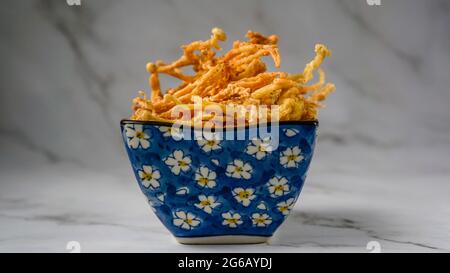 Crunchy deep fried Enoki Mushrooms with chilli flakes. Delicious snacks. Stock Photo