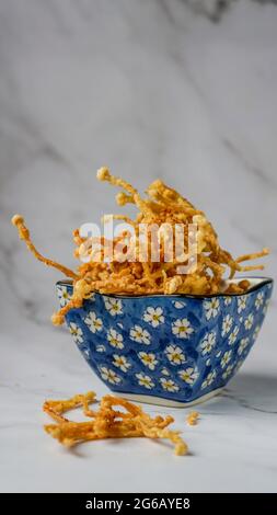 Crunchy deep fried Enoki Mushrooms with chilli flakes. Delicious snacks. Stock Photo