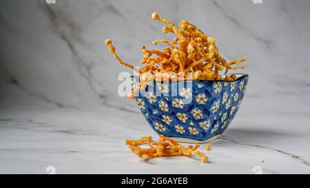 Crunchy deep fried Enoki Mushrooms with chilli flakes. Delicious snacks. Stock Photo