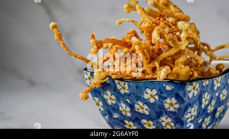 Crunchy deep fried Enoki Mushrooms with chilli flakes. Delicious snacks. Stock Photo