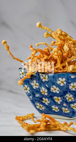 Crunchy deep fried Enoki Mushrooms with chilli flakes. Delicious snacks. Stock Photo