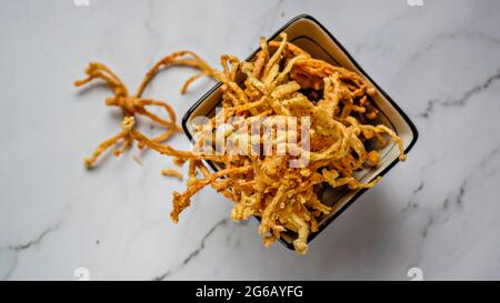 Crunchy deep fried Enoki Mushrooms with chilli flakes. Delicious snacks. Stock Photo