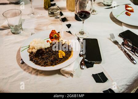 Typical Brazilian dish called Feijoada. Made with black beans, pork and sausage. Served on a white plate during a meeting. Stock Photo