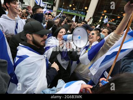 London, UK. 23rd May, 2021. A group of young protesters chant, dance and wave flags during the protest.Pro-Israeli demonstrators rally outside the Israeli embassy in High Street Kensington in support of the ceasefire agreed on May 21st. A small group of Palestinians turned up to counter demonstrate the Israeli demonstration however police formed a cordon between the two crowds to avoid any violence. (Photo by Martin Pope/ SOPA Images/Sipa USA) Credit: Sipa USA/Alamy Live News Stock Photo