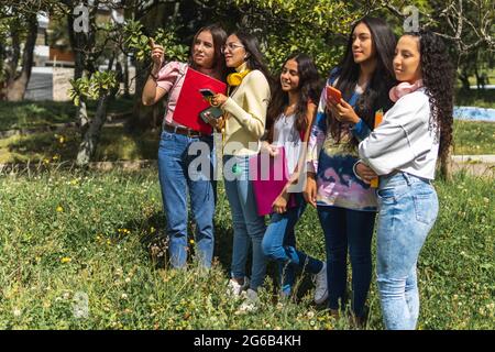 Portrait of Latinx teenagers in a park, students with backpacks, notebooks, cell phones and headphones. Back to school concept Stock Photo