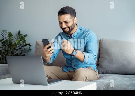 Indian business man screaming cheering reading great news on smartphone Stock Photo