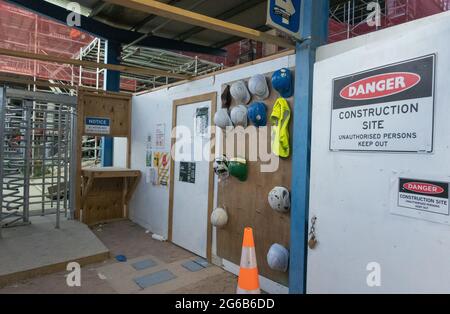 Tauranga New Zealand - July 2021; Worker entry to development and construction site of Farmers building with hardhats, vest and work and safety signs.