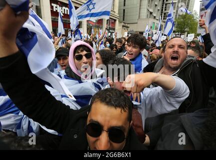 A group of young protesters chant, dance and wave flags during the protest.Pro-Israeli demonstrators rally outside the Israeli embassy in High Street Kensington in support of the ceasefire agreed on May 21st. A small group of Palestinians turned up to counter demonstrate the Israeli demonstration however police formed a cordon between the two crowds to avoid any violence. Stock Photo