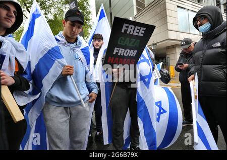 London, UK. 23rd May, 2021. Protesters hold Israeli flags and placards during the protest.Pro-Israeli demonstrators rally outside the Israeli embassy in High Street Kensington in support of the ceasefire agreed on May 21st. A small group of Palestinians turned up to counter demonstrate the Israeli demonstration however police formed a cordon between the two crowds to avoid any violence. Credit: Martin Pope/SOPA Images/ZUMA Wire/Alamy Live News Stock Photo