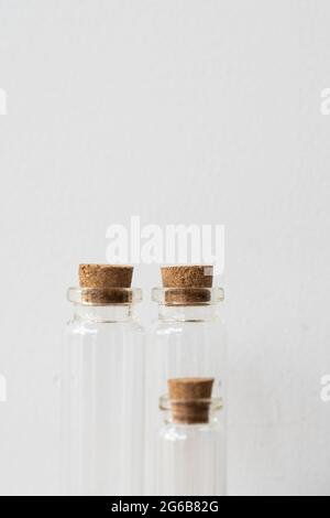Three glass bottles with cork stopper on wooden podium with white wall background. Essential oil refilling store. Mockup template.  Stock Photo