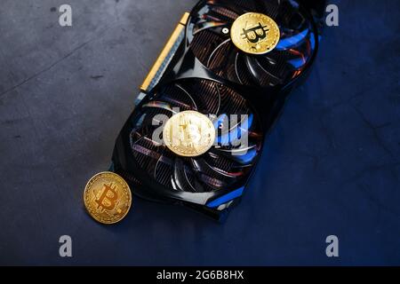 Gold Bitcoin on the video card cooler on a dark background top view. The concept of mining and mining of cryptocurrency, the device of a cryptocurrenc Stock Photo