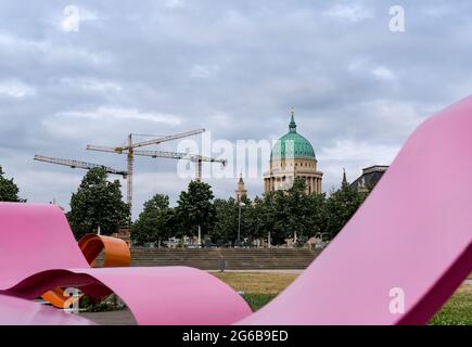 Potsdam, Germany. 22nd June, 2021. View of the Nikolai Church at the Old Market Square, which is surrounded by building cranes, over artistically designed coloured figures in the garden Lustgarten in the city centre. Credit: Jens Kalaene/dpa-Zentralbild/ZB/dpa/Alamy Live News Stock Photo