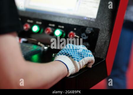 Worker controls modern computerized machine in metalworking plant. Selective focus. Stock Photo