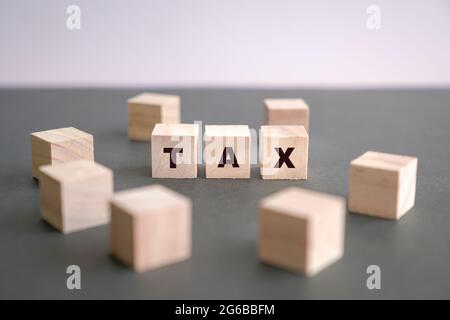 TAX written on wooden blocks on dark grey background. Taxation concept. Stock Photo