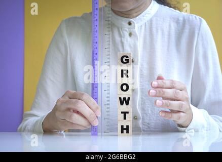 Businesswoman measure growth written on wooden cubes using ruler. Business performance concept. Stock Photo