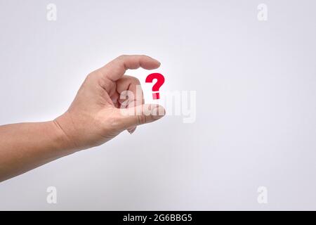 Man's fingers virtually hold a red question mark on white background. Copy space. Stock Photo