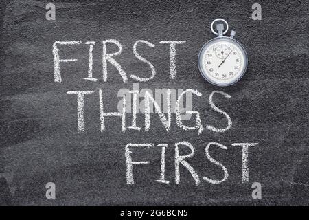 first things first phrase written on chalkboard with vintage precise stopwatch Stock Photo