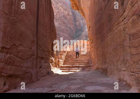 Rear view of a woman walking up stairs in ancient city of Petra, Jordan