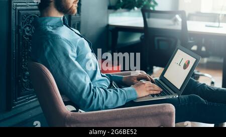 Young focused faceless man trader working on laptop computer Stock Photo