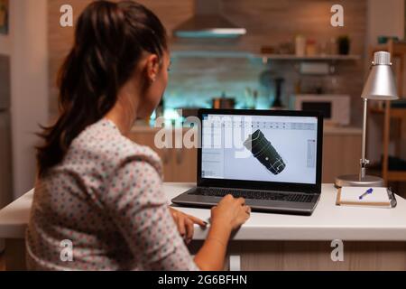 Back view of engineer working on turbine project in home office during night time. Industrial female engineer working on personal computer showing cad software. Stock Photo