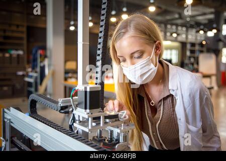 Female engineer or technician is working, examining or repairing automatic robot equipment hardware in the lab or laboratory to upgrade processor chip Stock Photo