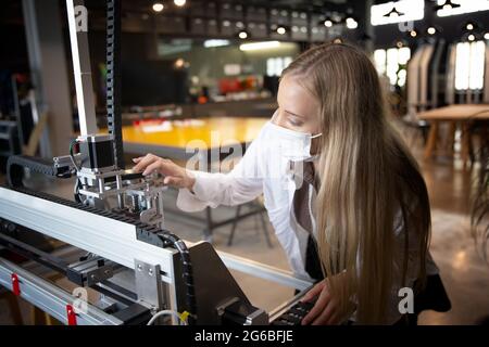 Female engineer or technician is working, examining or repairing automatic robot equipment hardware in the lab or laboratory to upgrade processor chip Stock Photo