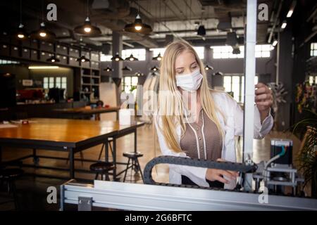 Female engineer or technician is working, examining or repairing automatic robot equipment hardware in the lab or laboratory to upgrade processor chip Stock Photo