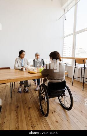 Three multiracial women discussing project while having break in office Stock Photo