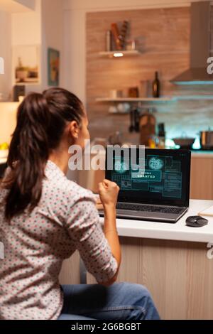 Happy woman hacker after cracking firewall of government and getting access granted. Programmer writing a dangerous malware for cyber attacks using performance laptop during midnight. Stock Photo