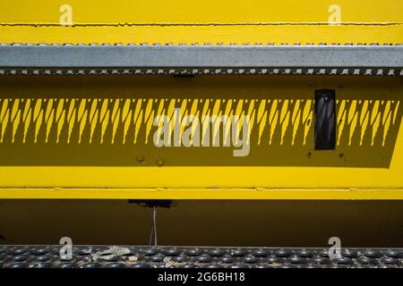 Shadows fall on the yellow plate of farm machinery Stock Photo