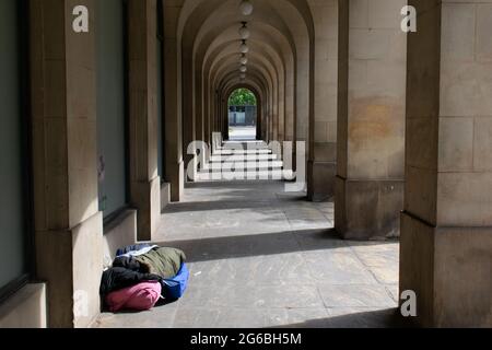 Homeless person in sleeping bag under arches of Manchester Town Hall Extension Stock Photo