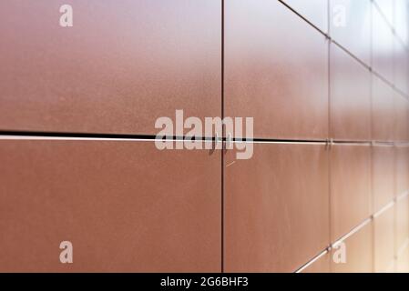 Background texture of rectangular smooth brown tiles. Stone street covering of wall, masonry of building.Brown stone panels for ventilated walls or fa Stock Photo