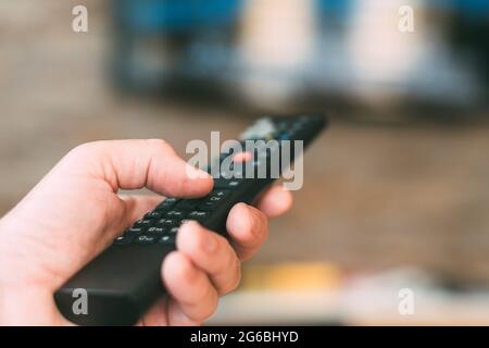 Male hand holding television remote controller, close up with selective focus Stock Photo