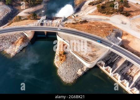 Top down aerial view over concrete dam, road and bridge across Snowy river, Jindabyne lake of Australia. Stock Photo