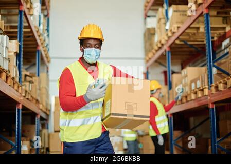 Male worker with box using smartphone in warehouse Stock Photo