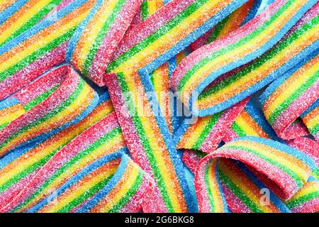 Colorful jelly candies in sugar sprinkles. Sour flavored rainbow candy background. Top view Stock Photo