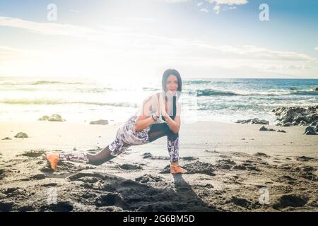 woman in sport clothes practicing yoga and meditating on beach in morning Stock Photo