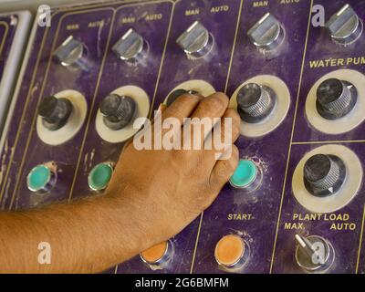 Asian male technician operating hydraulic machine at construction sight. Stock Photo