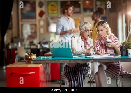 Female colleagues in a pleasant atmosphere in the office are shocked by data they read from documents Stock Photo