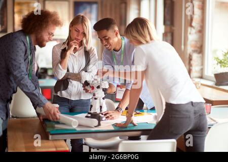 Group of young creative people is analyzing a robot toy at work in a working atmopshere in the office Stock Photo