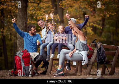 A happy family posing for a photo on a break of hiking in the forest on a beautiful autumn day Stock Photo