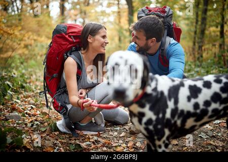 Hikers couple in love taking a break at hiking with their dog Stock Photo
