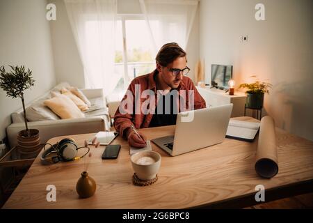 Caucasian male studying online working from home on laptop during lockdown Stock Photo