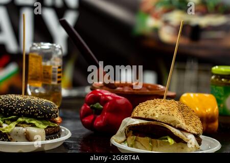 Two cheese burgers on a table with red and yellowe peppers in background on street food counter Stock Photo