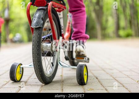 Close-up of a child rides a bicycle with three wheels. Stock Photo