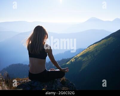 View from shoulder young slim woman doing meditation on fresh air. Concept of harmony with nature. Stock Photo
