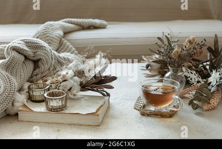 Glass cup of tea, knitted element and dried flowers in the interior of the room. Stock Photo