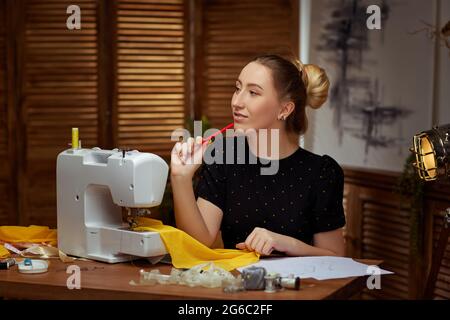 Beautiful young seamstress working on sewing machine Stock Photo